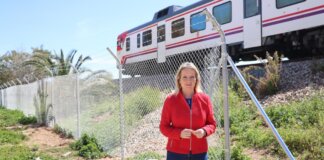 Mujer de pie junto a un vallado con tren en el fondo en Xirivella