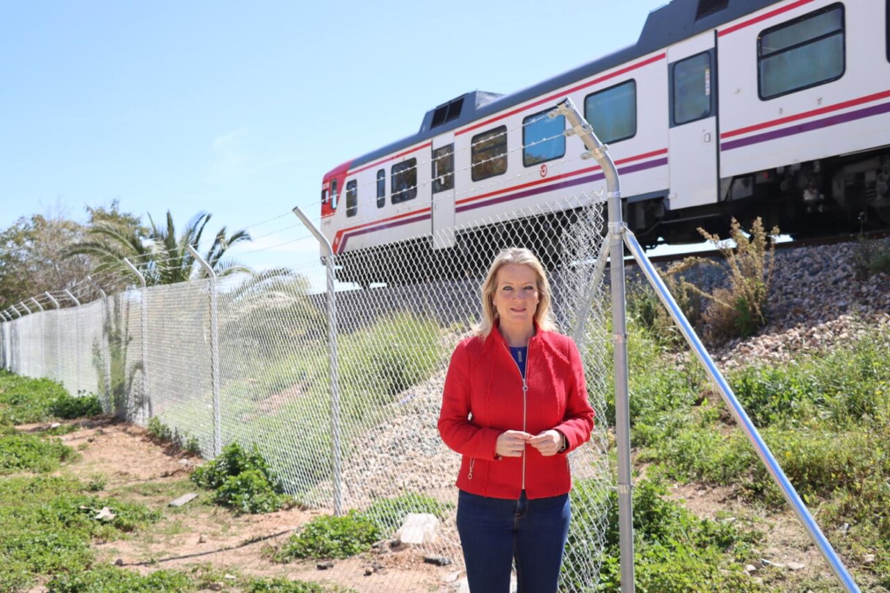 Mujer de pie junto a un vallado con tren en el fondo en Xirivella