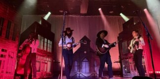 The Dead South actuando en el Auditorio Roig Arena con iluminación colorida.