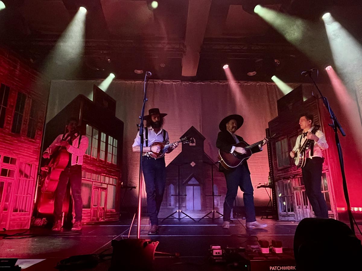 The Dead South actuando en el Auditorio Roig Arena con iluminación colorida.
