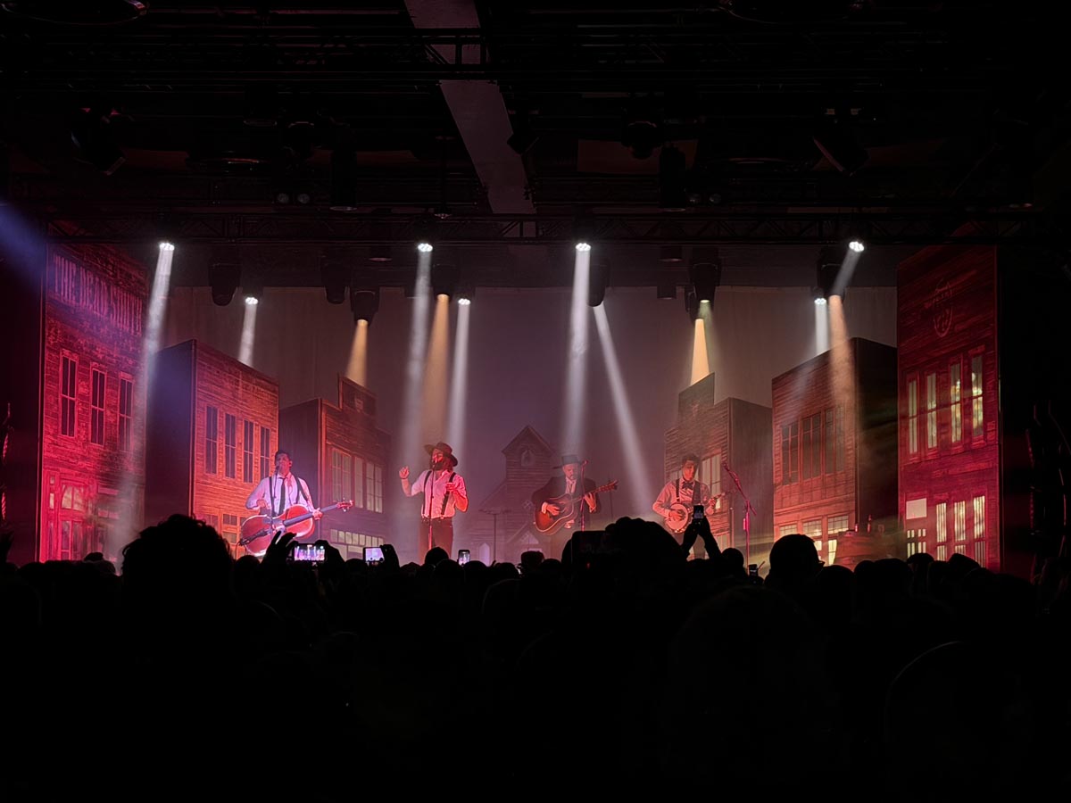The Dead South actuando en el Auditorio Roig Arena con fondo de escenario iluminado