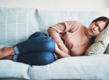 Mujer con dolor abdominal en un sofá