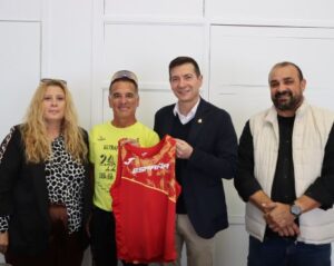 Eduardo L. Gómez posando con su equipo y camiseta en un evento deportivo