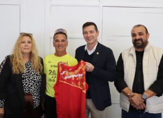 Eduardo L. Gómez posando con su equipo y camiseta en un evento deportivo
