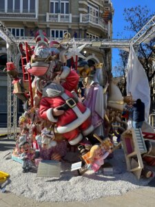 Figuras navideñas en una escena festiva con Santa Claus y niños.