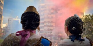 Dos falleras observando una mascletà en Torrent con humo de colores