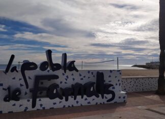 Cartel de la Pobla de Farnals junto a la playa con cielo nublado