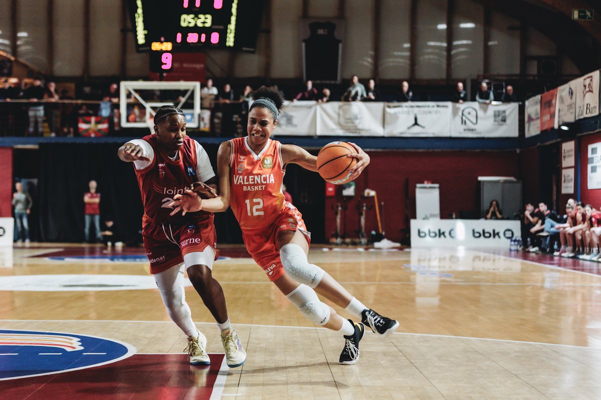 Jugadora de Valencia Basket driblando mientras es defendida por una oponente.