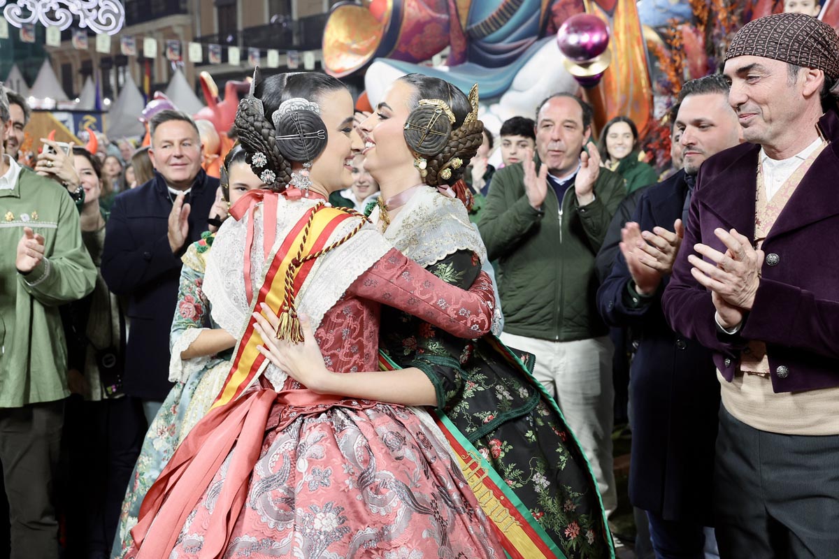 Dos mujeres en trajes tradicionales se abrazan durante la celebración de Fallas.