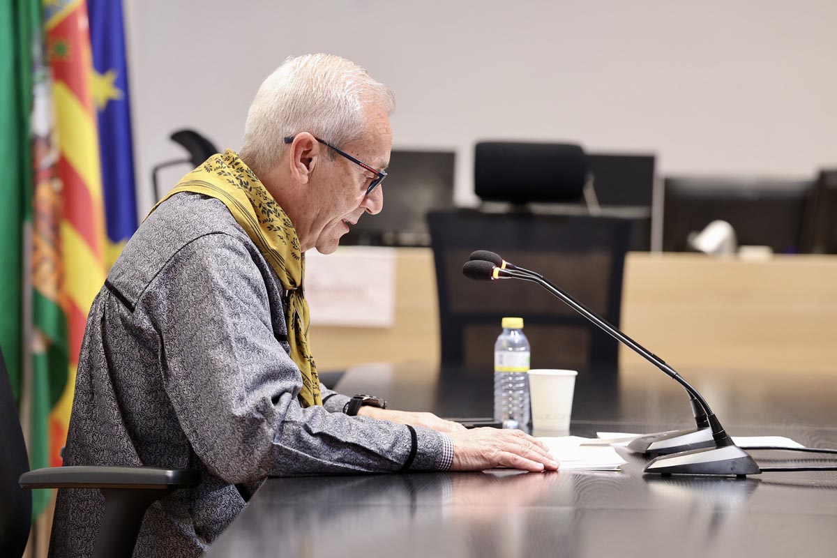 Hombre leyendo en una mesa con micrófono y botellas de agua