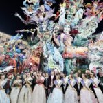 Grupo de personas en trajes tradicionales frente a una falla en la celebración de Fallas 2026.