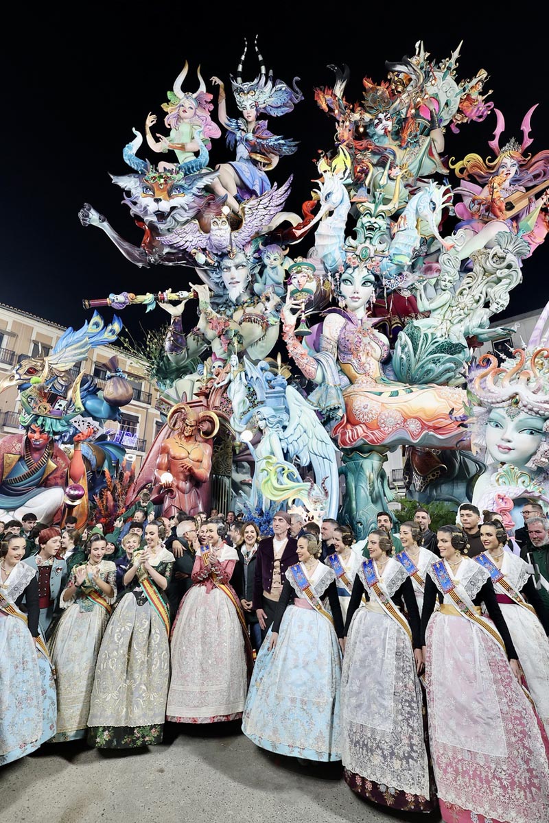 Grupo de personas en trajes tradicionales frente a una falla en la celebración de Fallas 2026.