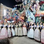 Grupo de personas en trajes tradicionales frente a monumento de Fallas