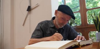 José Antonio Orts escribiendo en un libro en un ambiente artístico.