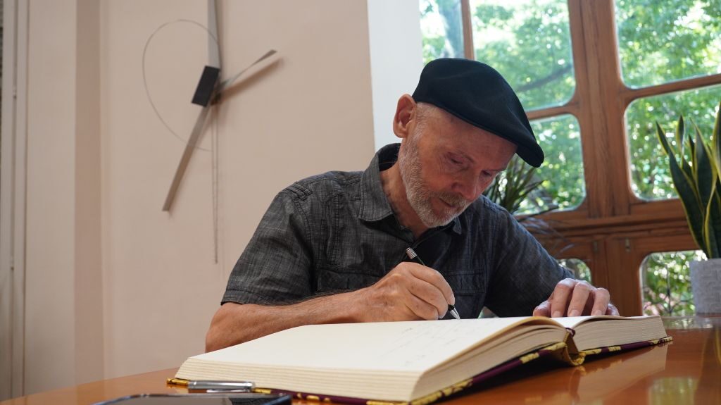José Antonio Orts escribiendo en un libro en un ambiente artístico.