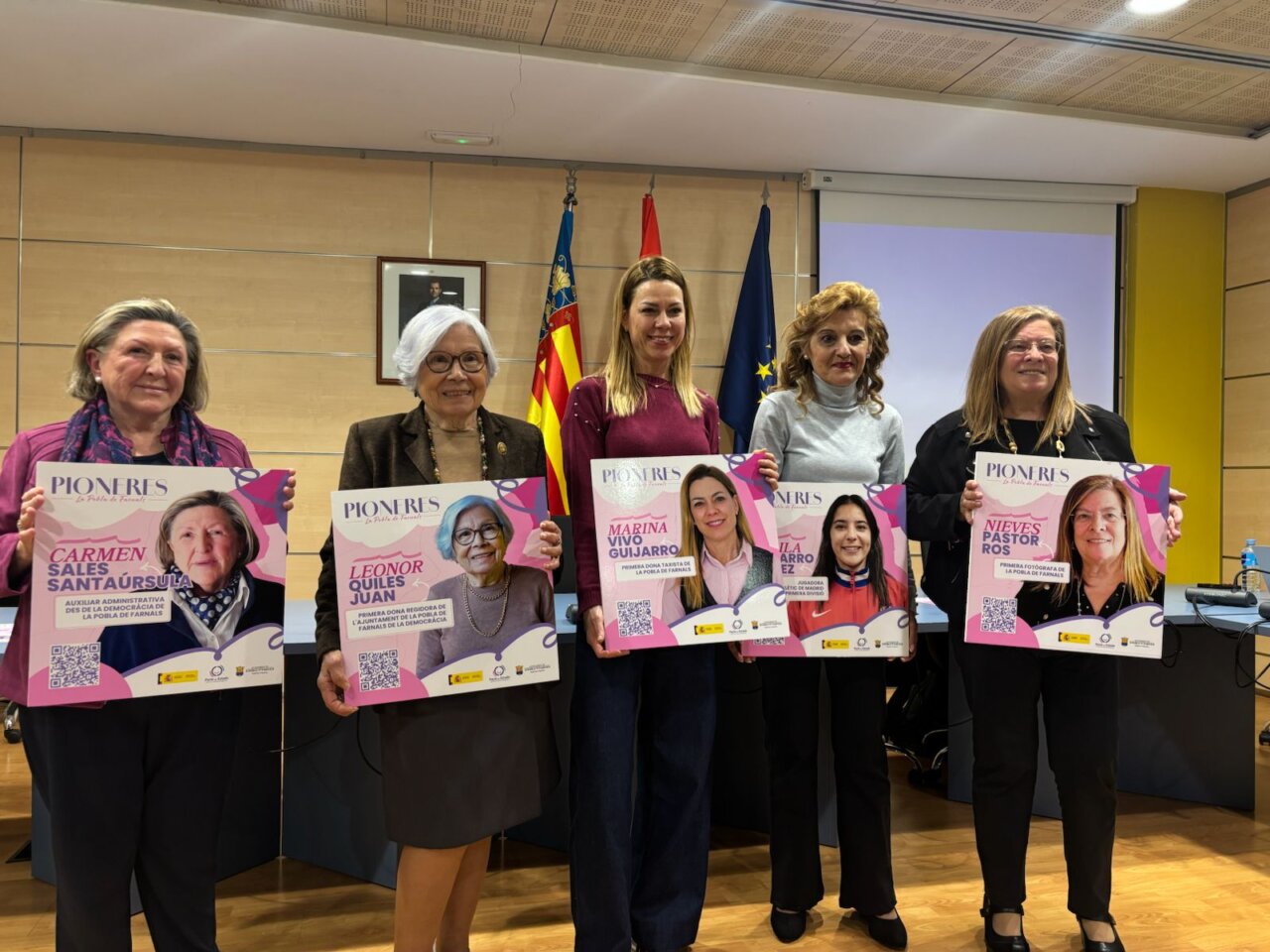 Cinco mujeres pioneras sosteniendo carteles con sus nombres y logros