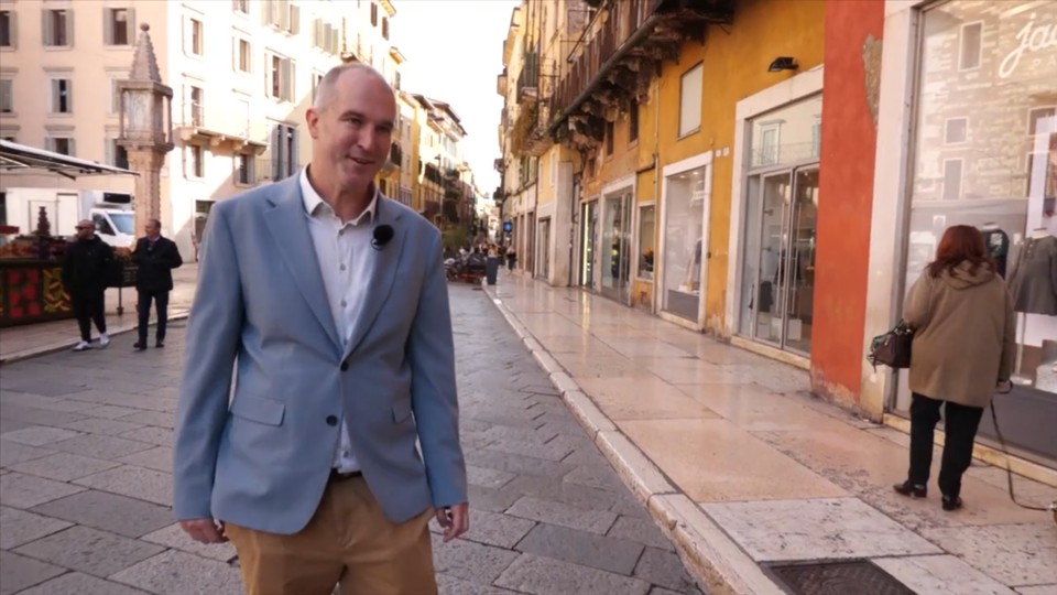 Hombre caminando por una calle de Llombardia con edificios coloridos.