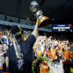 Jugadora de Valencia Basket levantando el trofeo con aficionados celebrando.