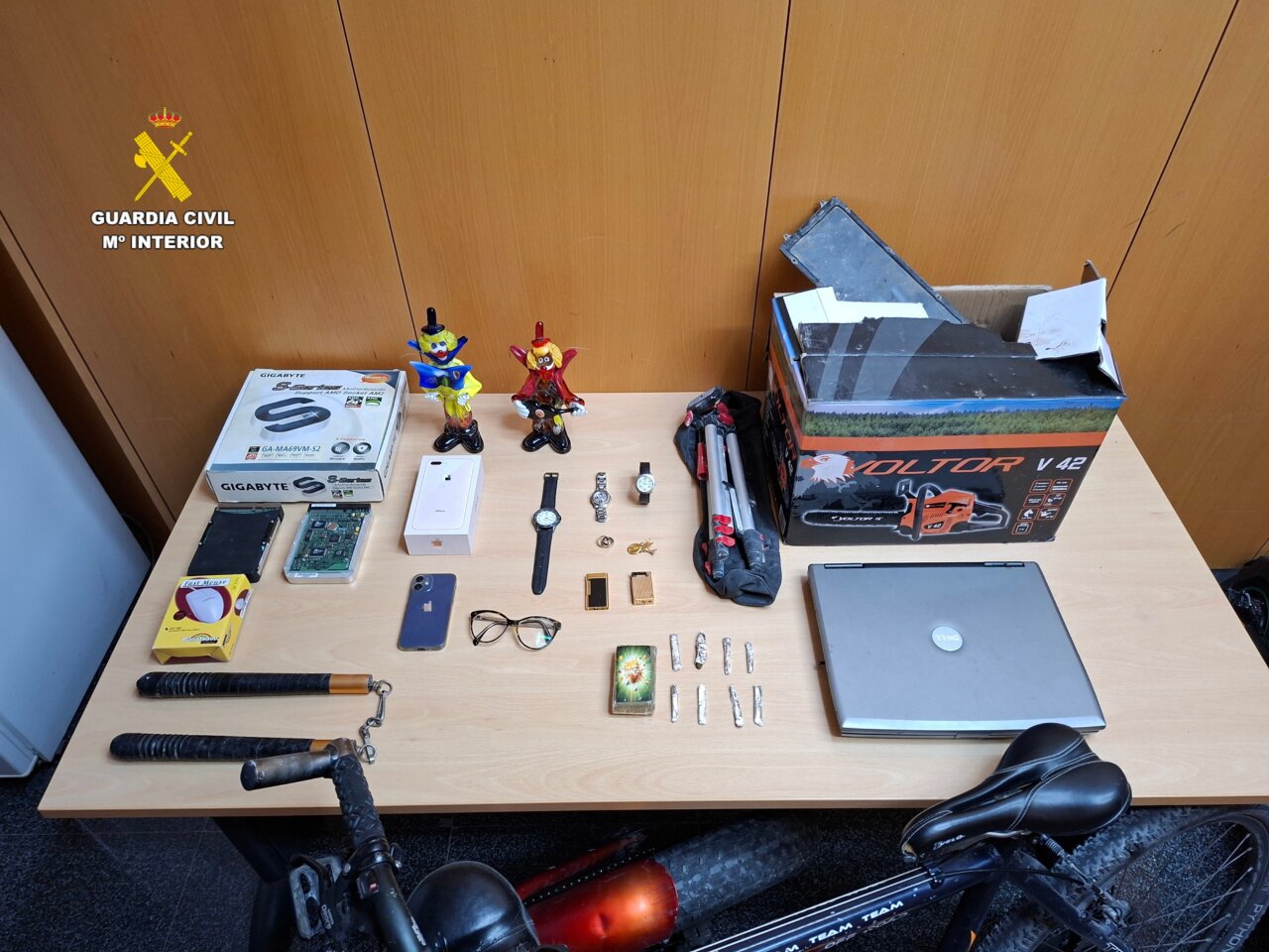 Mesa con objetos recolectados por la Guardia Civil, incluyendo dispositivos electrónicos y juguetes.