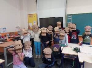 Grupo de escolares con máscaras de cartón en un aula