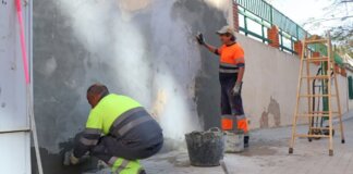 Trabajadores reparando la pared de la Escuela de Adultos Enric Valor en Xirivella