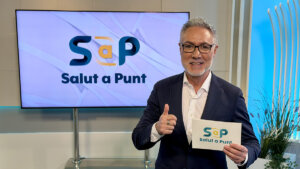 Presentador de Salut a Punt mostrando una tarjeta con el logo del programa