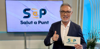 Presentador de Salut a Punt mostrando una tarjeta con el logo del programa