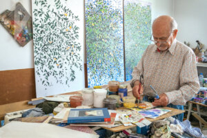 Salvador Montesa trabajando en su taller rodeado de pinturas y materiales artísticos.