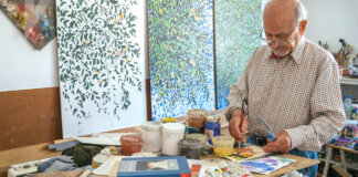 Salvador Montesa trabajando en su taller rodeado de pinturas y materiales artísticos.