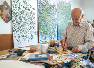 Salvador Montesa trabajando en su taller rodeado de pinturas y materiales artísticos.
