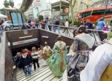 Personas en trajes tradicionales accediendo a la estación de metro Ángel Guimerá durante las Fallas.