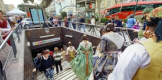 Personas en trajes tradicionales accediendo a la estación de metro Ángel Guimerá durante las Fallas.