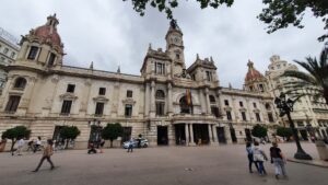 Vista del Ajuntament de València con personas y vehículos en la calle.