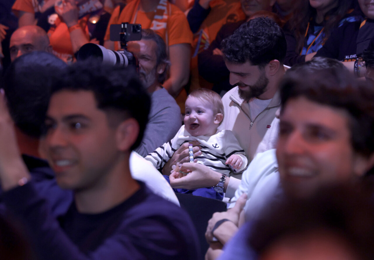 Un padre sostiene a su bebé sonriente en un evento de Valencia Basket.