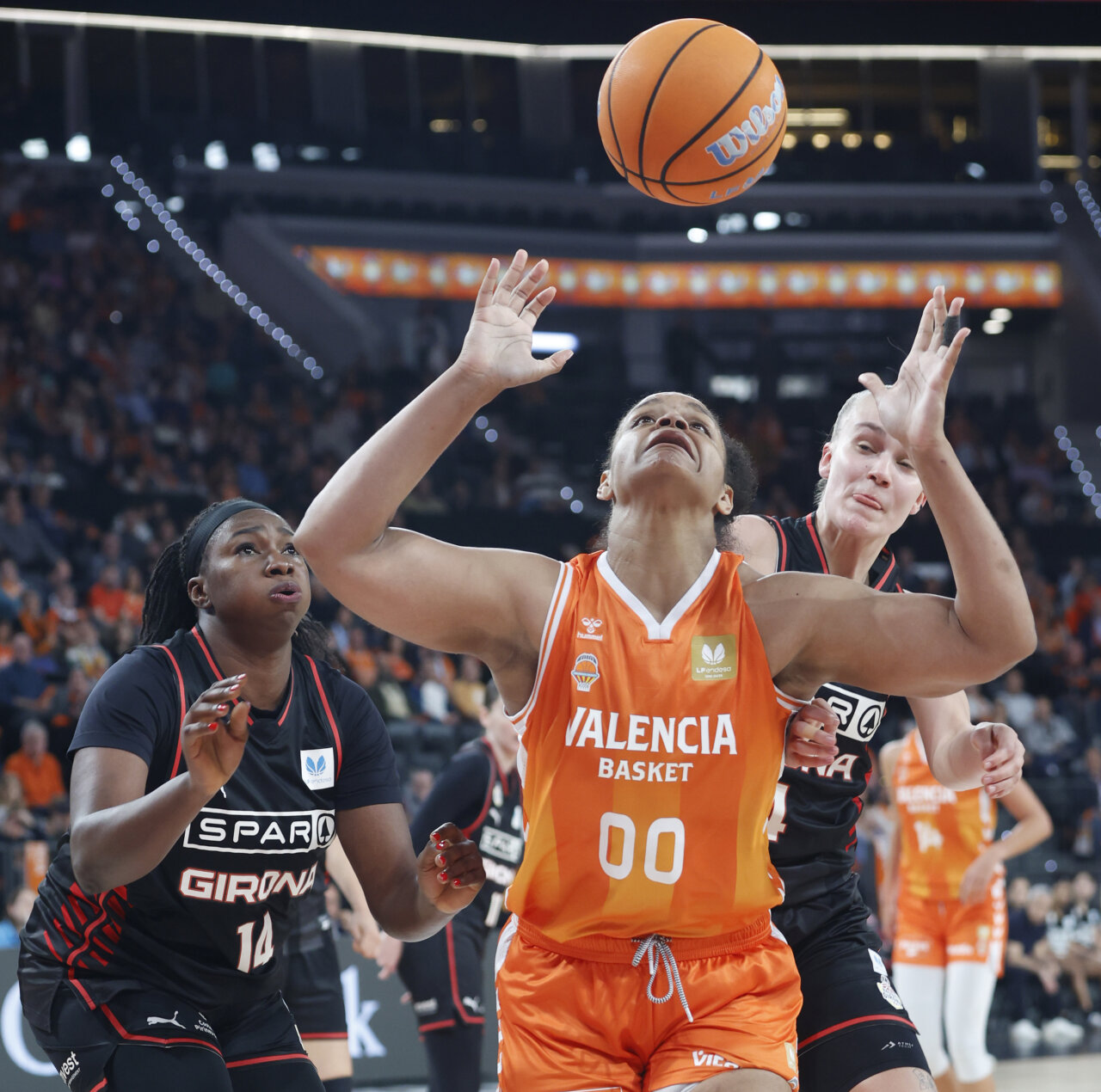 Jugadoras de Valencia Basket y Spar Girona compiten por el balón en un partido de baloncesto.