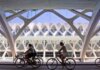 Ciclistas pasando por un moderno edificio en Valencia