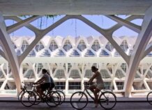 Ciclistas pasando por un moderno edificio en Valencia