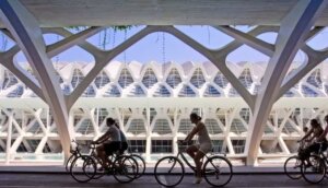 Ciclistas pasando por un moderno edificio en Valencia