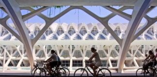 Ciclistas pasando por un moderno edificio en Valencia
