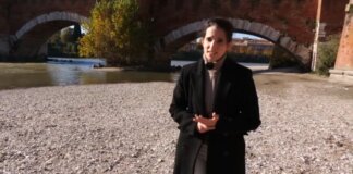 Mujer en la orilla de un río con un puente de fondo