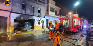Un coche de Policía Nacional se empotra tras una persecución en una casa en Alaquàs causando un incendio Bomberos trabajando en un incendio de un vehículo contra una vivienda en Alaquas
