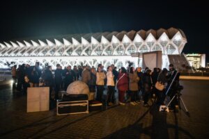 Grupo de personas en actividades de divulgación frente a un museo iluminado