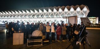 Grupo de personas en actividades de divulgación frente a un museo iluminado