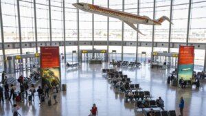 Interior del aeropuerto de Manises en Valencia con pasajeros y un avión colgado