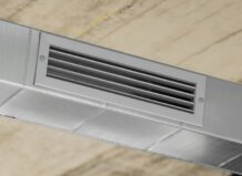 Aire acondicionado por conductos: ventajas que explican su creciente demanda Rejilla de aire acondicionado por conductos en un techo moderno