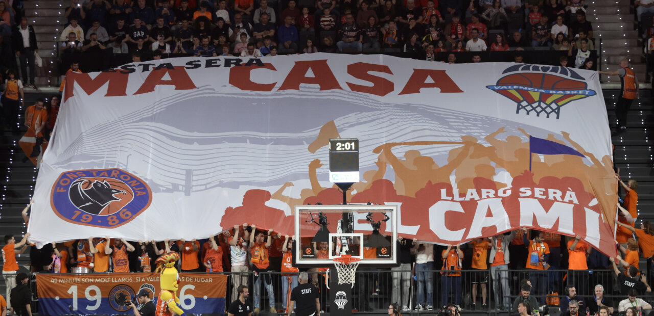 Aficionados de Valencia Basket sosteniendo una gran pancarta en el Roig Arena.