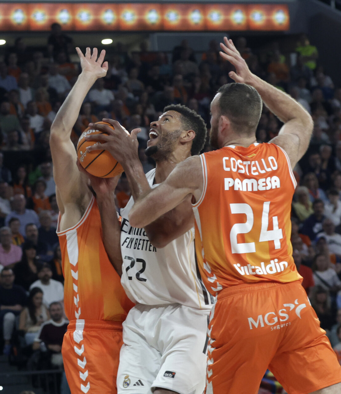 Jugadores del Valencia Basket y Real Madrid en acción durante un partido de baloncesto.