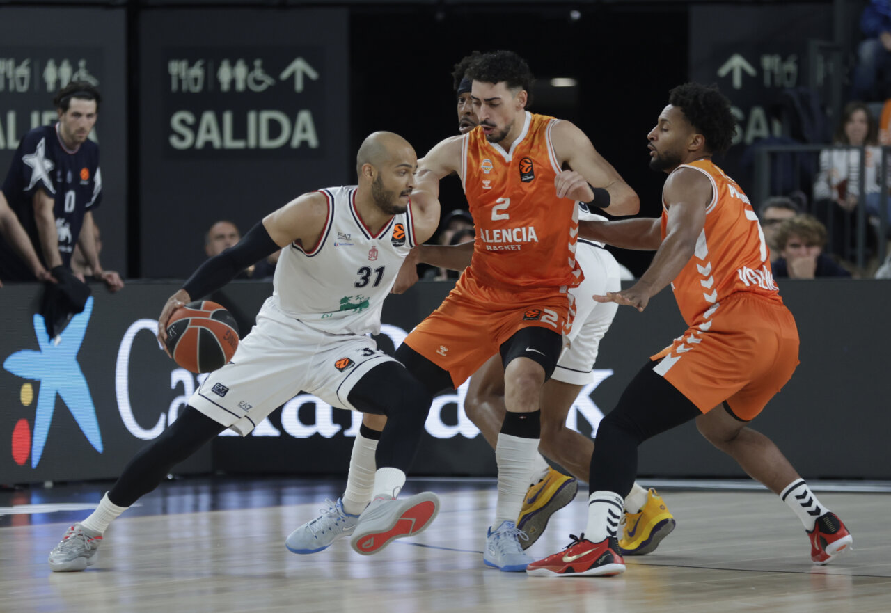 Jugadores de Valencia Basket y Olimpia de Milán compiten en un partido de baloncesto.