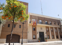 Fachada del Ayuntamiento de Puçol con naranjos y banderas