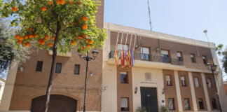 Fachada del Ayuntamiento de Puçol con naranjos y banderas